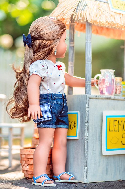 a doll is standing in front of a lemonade stand with her hair blowing out