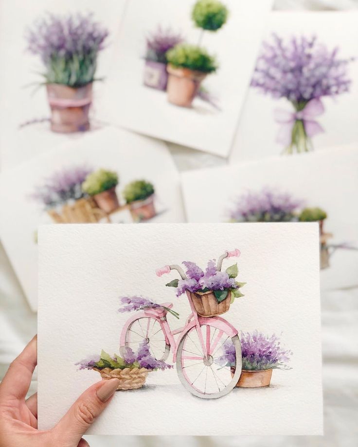 a person holding up some cards with flowers on them and a bicycle in the middle