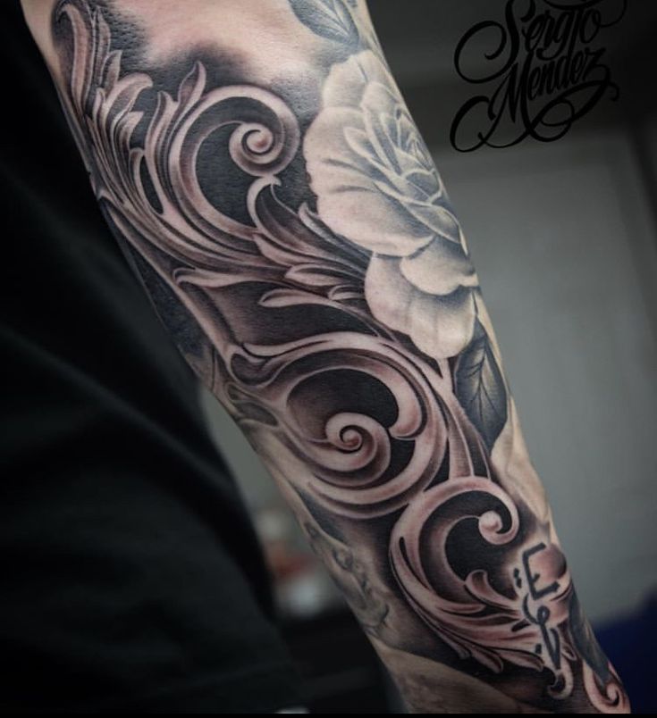 a man's arm with flowers and swirls in black and grey ink on it