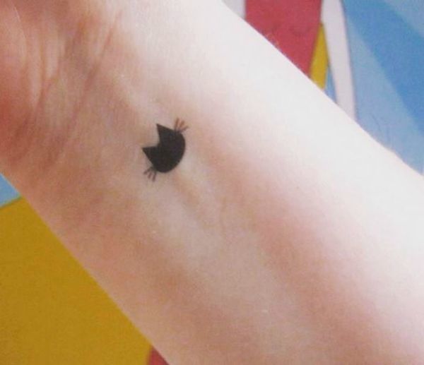 a small black apple tattoo on the wrist