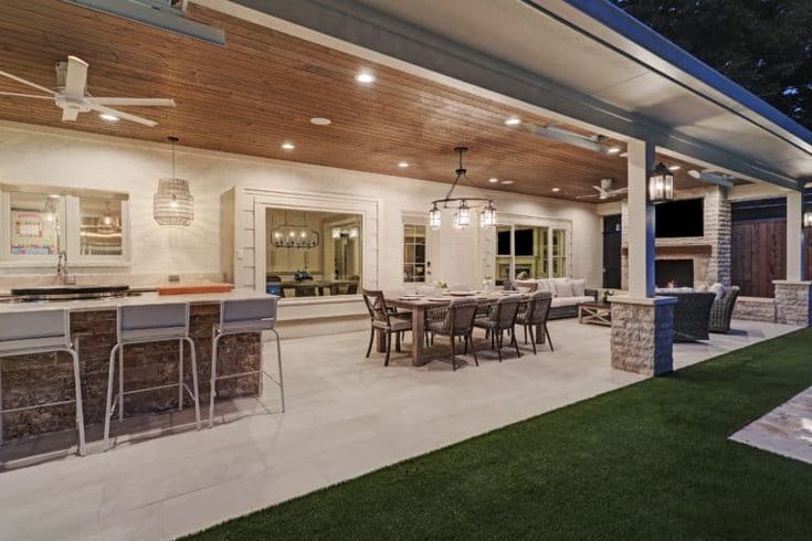 an outdoor kitchen and dining area is lit up at night with lights on the ceiling