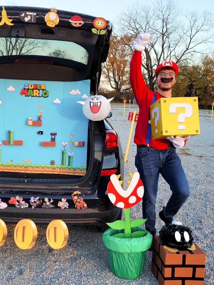 a man standing next to a car with mario bros decorations on it's trunk