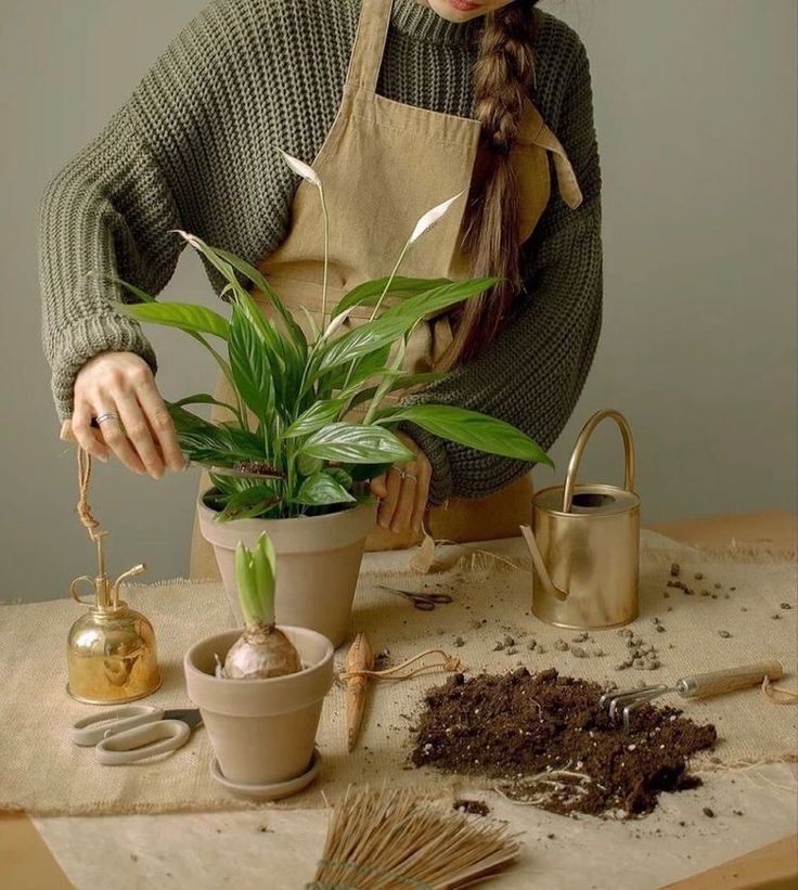 a woman in an apron is arranging plants on a table with gardening utensils