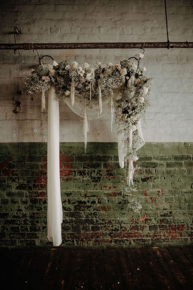 an arrangement of flowers hanging from the ceiling in front of a brick wall