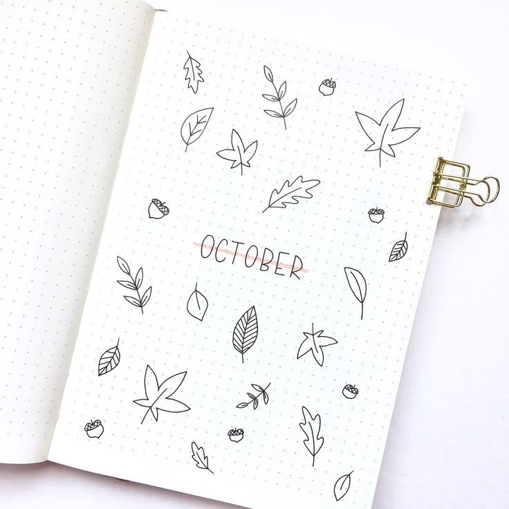 an open notebook with leaves and the word october written on it, sitting on top of a white surface