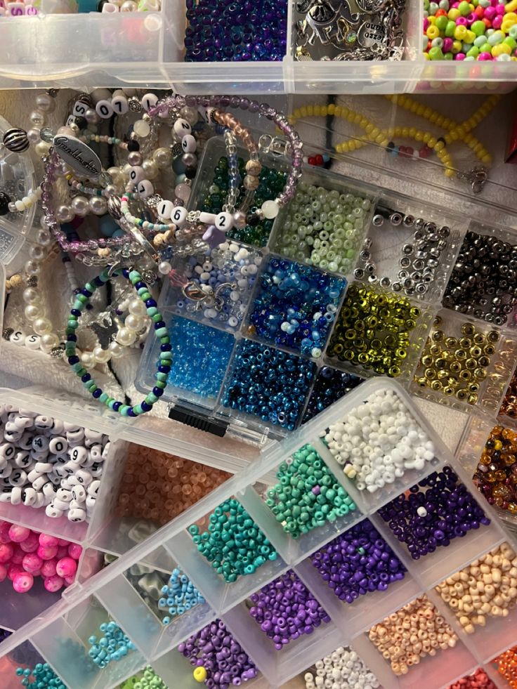 there are many different beads and necklaces in the bins on the table together