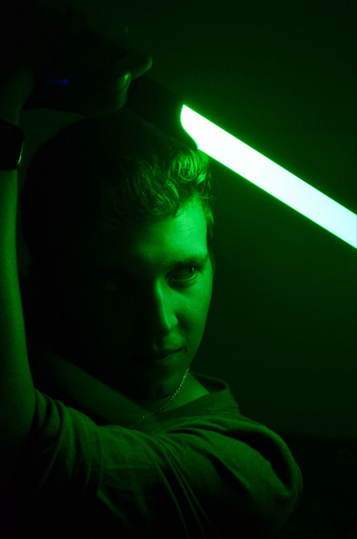 a man is holding his head in the dark with a green light shining on him