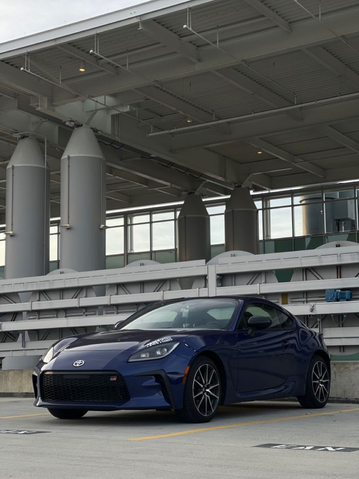 a blue sports car parked in front of a large building with columns on the roof