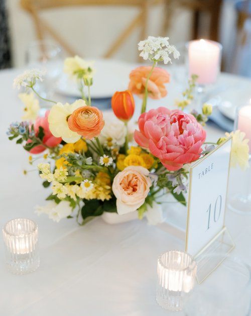 a vase filled with lots of flowers on top of a white table cloth covered table