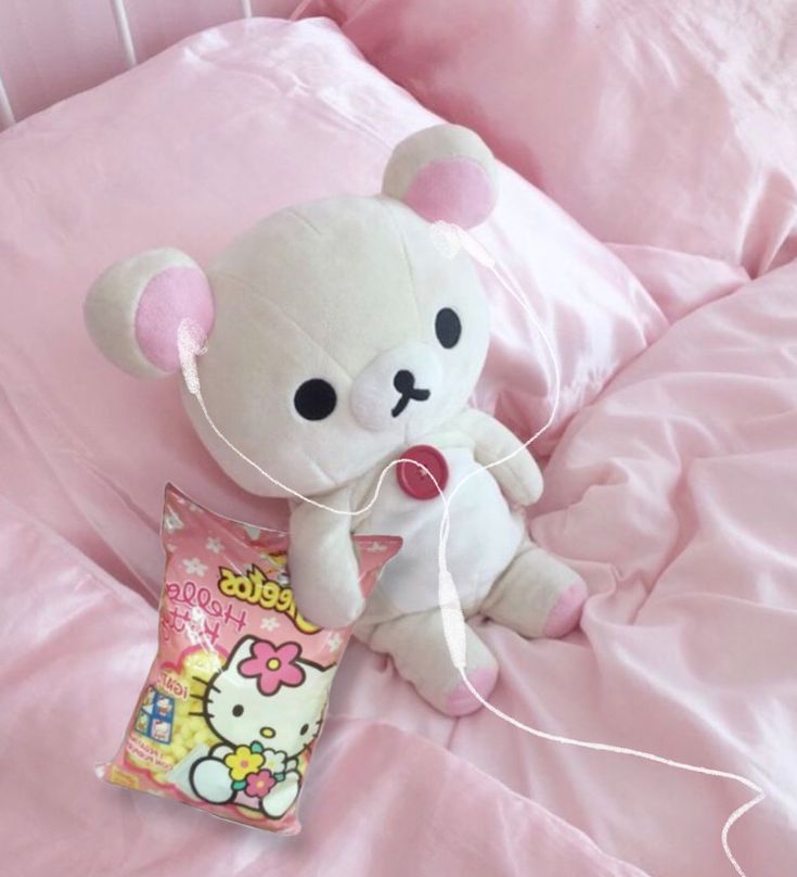 a white teddy bear sitting on top of a bed next to a package of candy