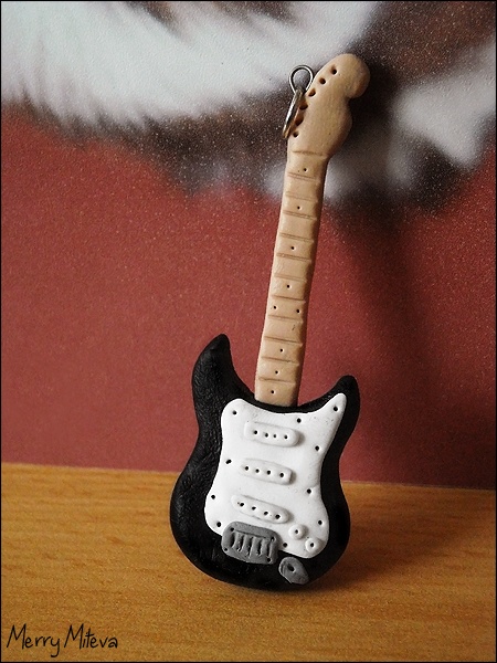 an electric guitar keychain made out of wood and plastic, on a table