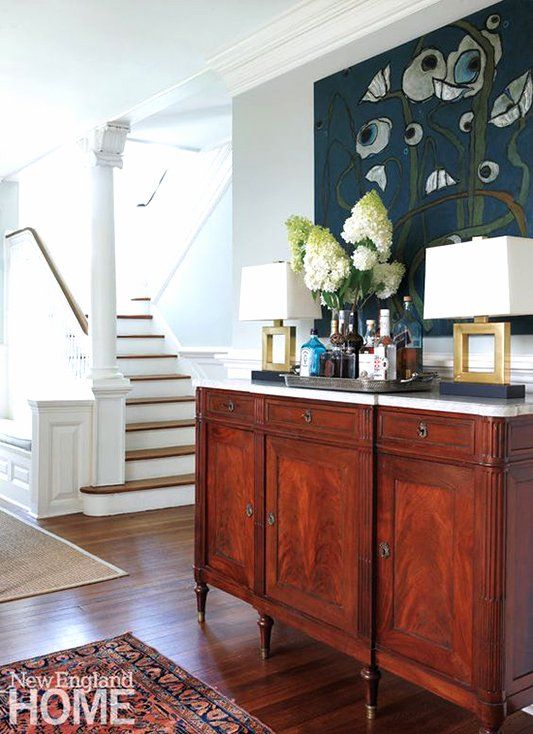 a living room with wooden floors and a painting on the wall next to a dresser