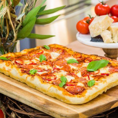 a pizza sitting on top of a wooden cutting board next to vegetables and cheeses