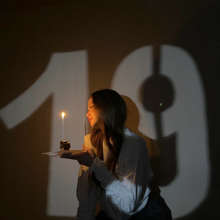 a woman holding a plate with a cake on it and a candle in her hand