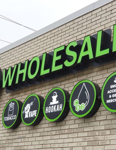 the wholesall sign is on the side of a building with green and black signs