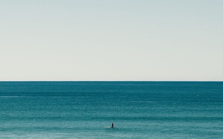 a lone surfer is out in the ocean on a clear day with no one around