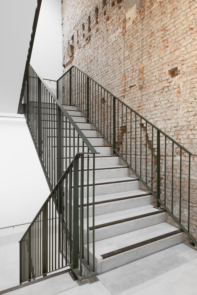 there is a set of stairs next to a brick wall and metal handrails