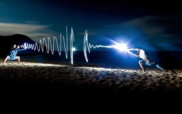 two people are dancing on the beach at night with their hands in front of them