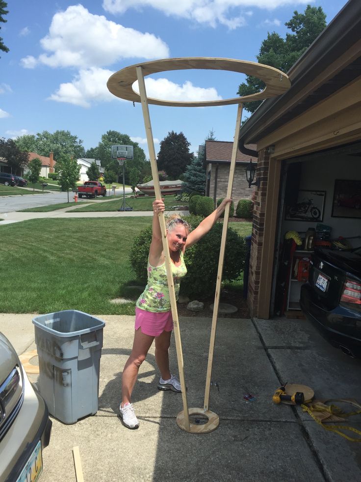 a woman is holding onto a pole in the driveway