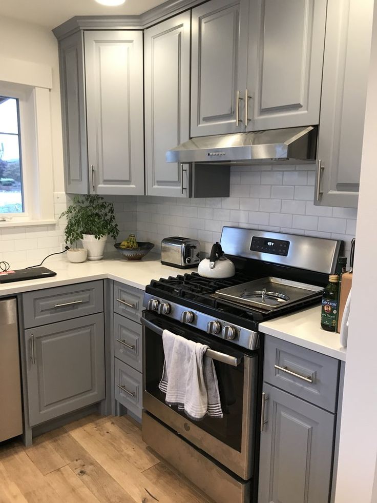 a kitchen with gray cabinets and stainless steel appliances