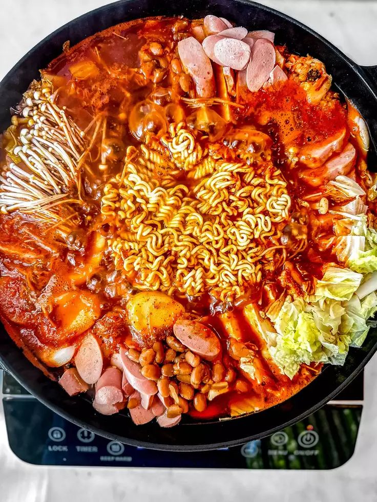 a pan filled with noodles and meats on top of a stove