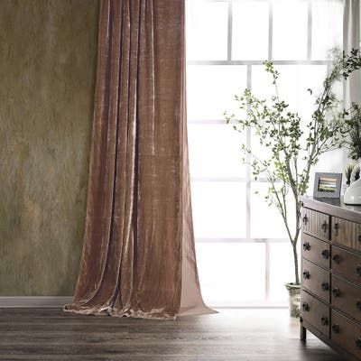 a room with a dresser, mirror and window covered in sheer drapes next to a potted plant