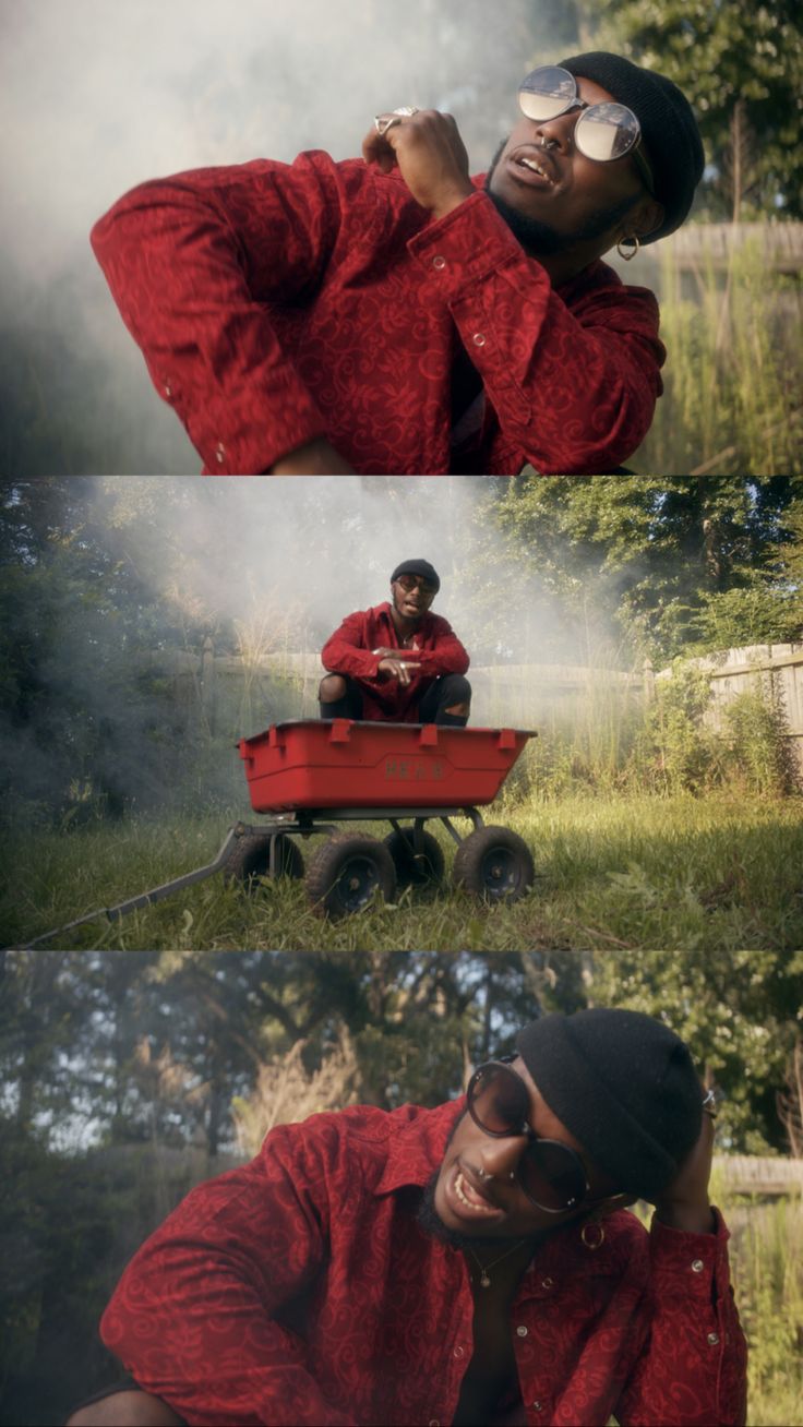 a man sitting on top of a red wagon next to another man in the grass