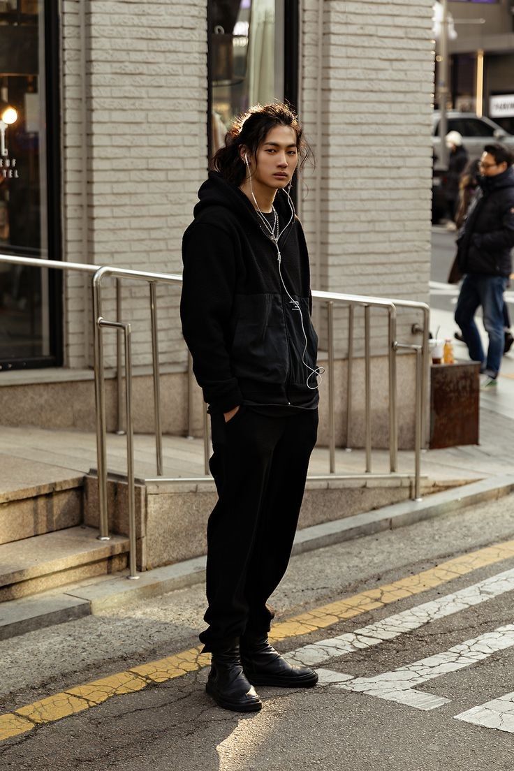 a young man is standing on the street listening to music