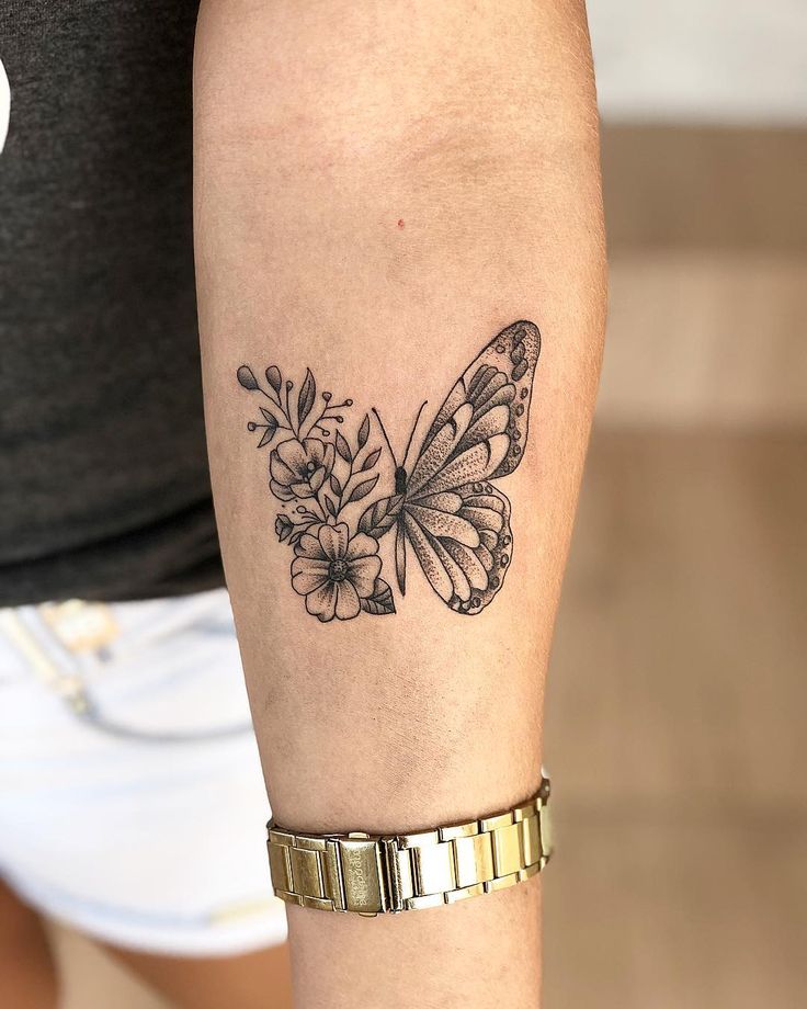 a woman's arm with a butterfly and flowers tattoo on it