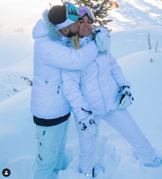 two people standing in the snow hugging each other