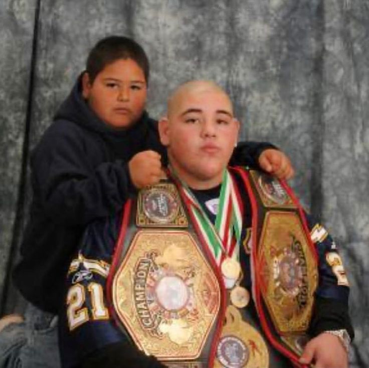 a young boy is holding his father's belt and posing for the camera while he stands next to him