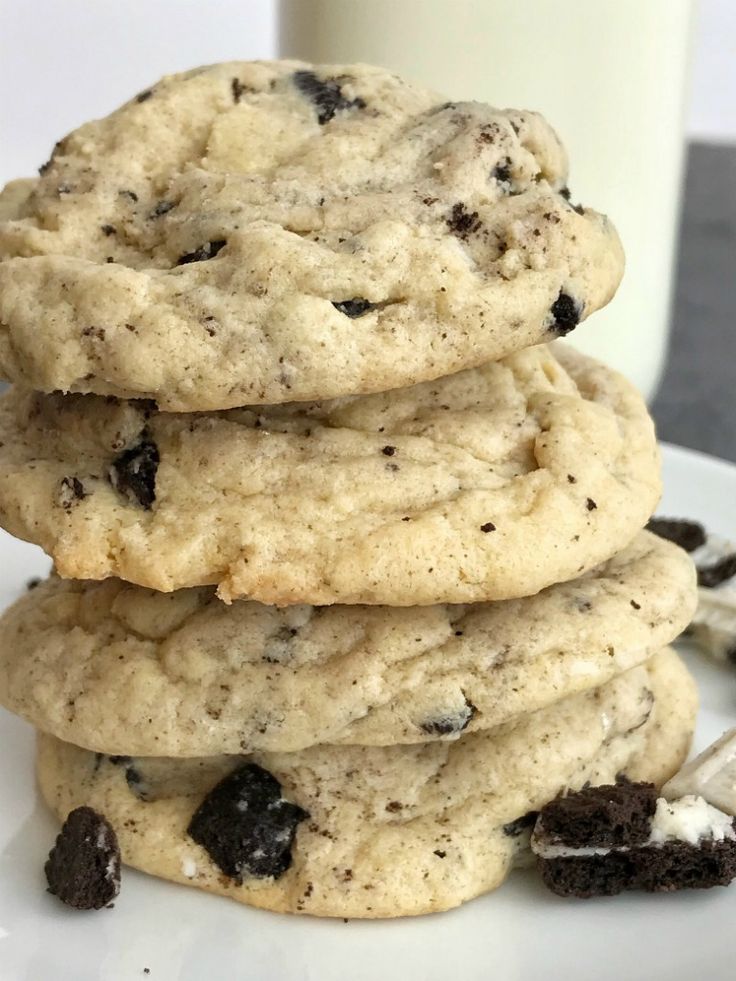 a stack of cookies sitting on top of a white plate next to a glass of milk