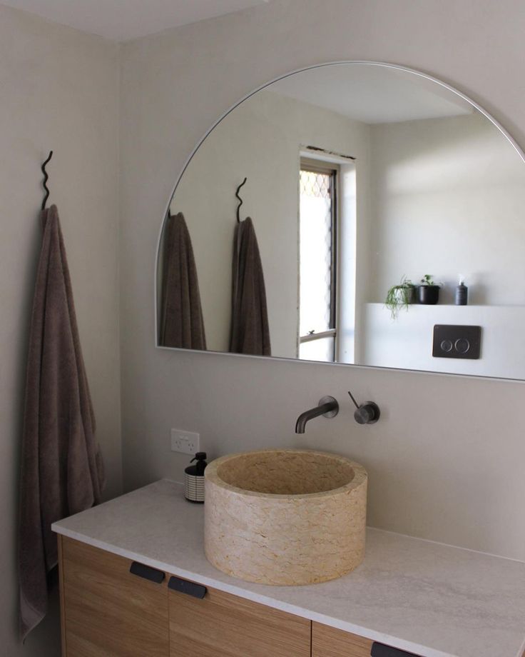 a bathroom sink under a large round mirror