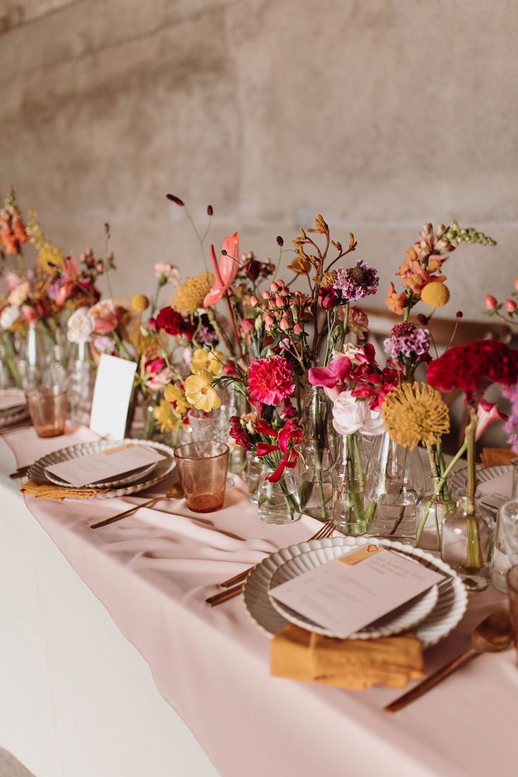 Place settings and table centrepiece flowers and decor with yellow and pink billy buttons, anthuriums and carnations