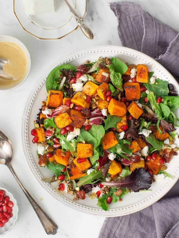 a white plate topped with a salad next to bowls of dressing