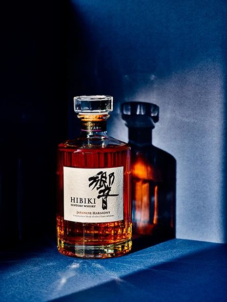 a bottle of liquor sitting on top of a blue shelf next to a glass vase