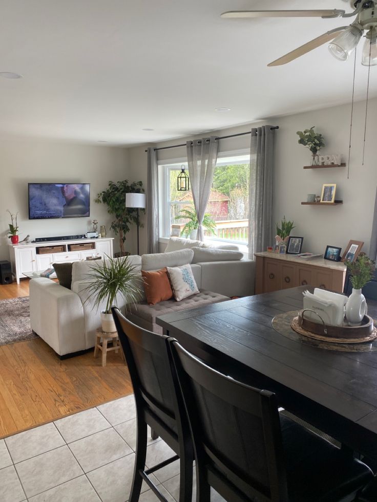 a living room filled with furniture and a flat screen tv mounted on the wall above a wooden dining table