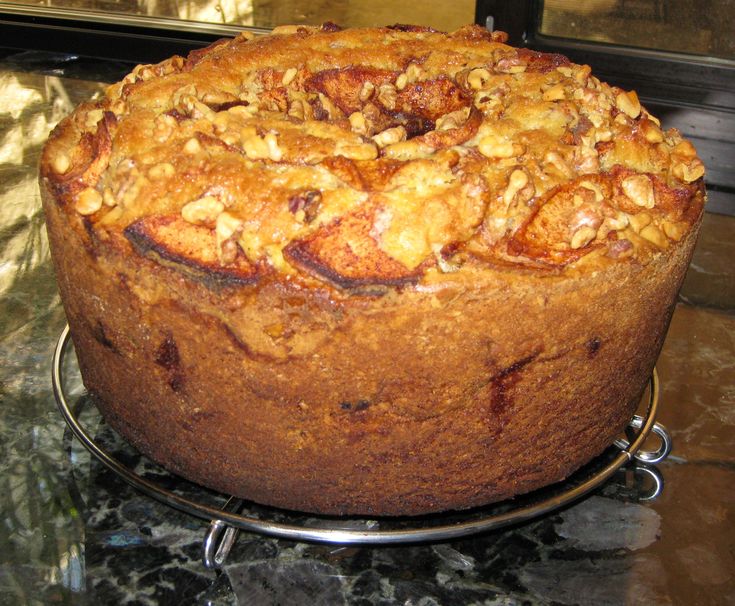 a cake sitting on top of a metal rack next to a glass table topped with fruit