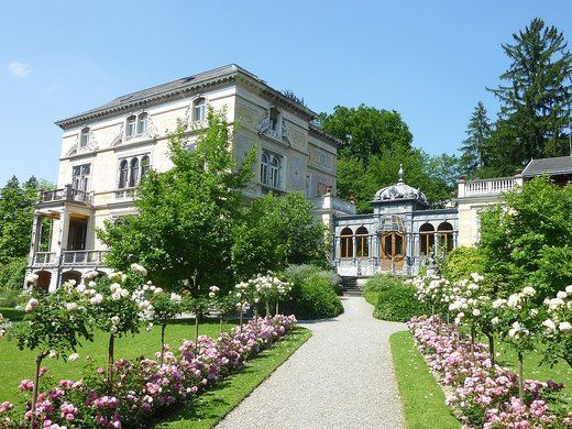 a large house surrounded by lush green trees and flowers