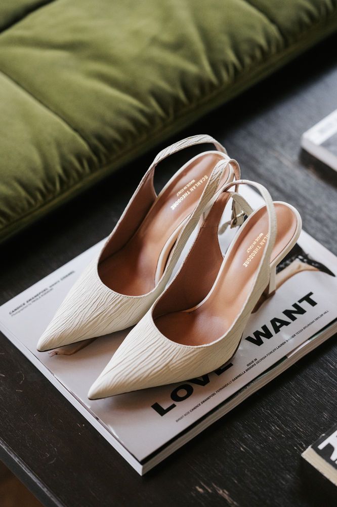 a pair of white high heels sitting on top of a magazine