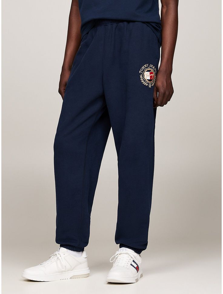 Tommy Hilfiger men's pant. These terry cotton joggers deliver on casual preppy style thanks to their elastic waistband and side slip pockets, sporting a luxe varsity-inspired embroidered take on our TJ logo. Part of our Tommy Jeans collection.  Material: 100% Transitional Cotton ,  In-conversion. Cotton Joggers With Logo Waistband For Jogging, Cotton Sweatpants With Logo Waistband For Sports, Sporty Joggers With Logo Waistband For Streetwear, Relaxed Fit Logo Waistband Joggers For Loungewear, Sporty Relaxed Fit Sweatpants With Logo Waistband, Casual Streetwear Sweatpants With Logo Waistband, Casual Cotton Joggers With Logo Waistband, Casual Sweatpants With Logo Waistband For Streetwear, Casual Relaxed Fit Sweatpants With Three Stripes