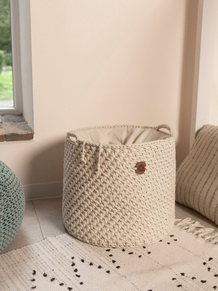 two round baskets sitting on the floor next to each other in front of a window