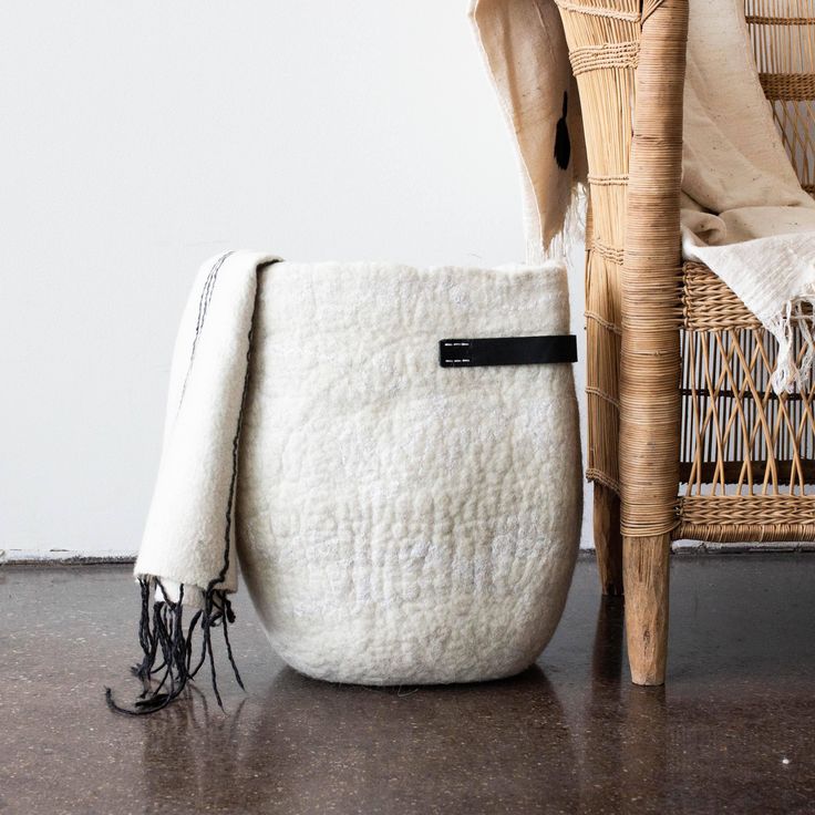 a wicker chair next to a large white bag on the floor in front of it