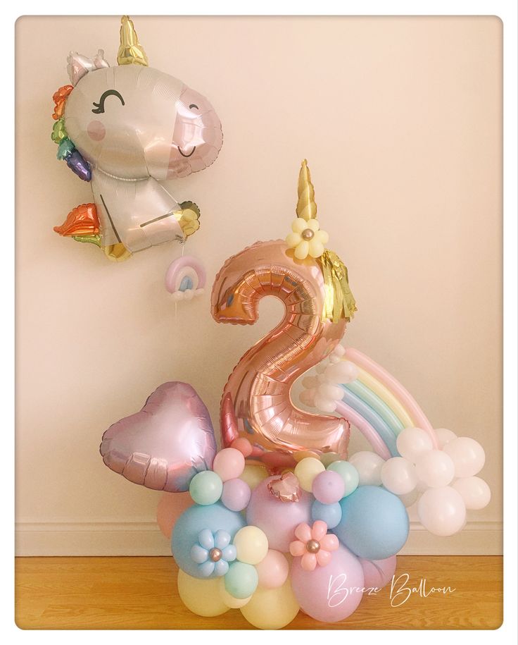 the number two balloon is in front of a unicorn balloon and some balloons are on the floor