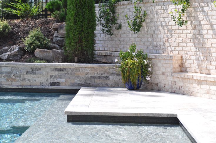 an outdoor swimming pool with steps leading up to it and plants growing on the wall