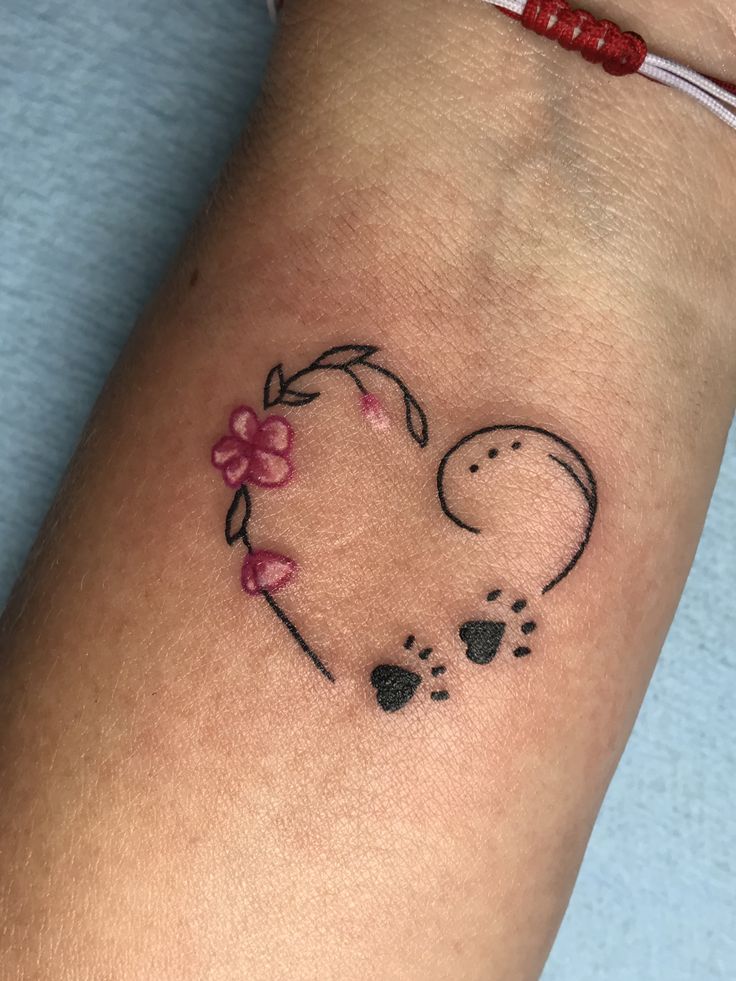 a small tattoo on the arm of a woman's leg with a heart and paw prints