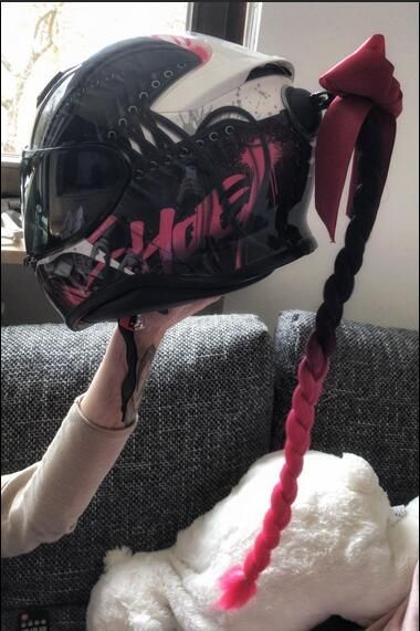 a person wearing a helmet with braids on their hair sitting on a couch next to a stuffed animal