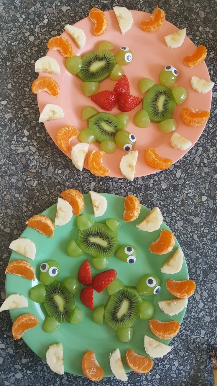 two plates that have fruit on them and eyes in the shape of fish made out of oranges, kiwis, and strawberries