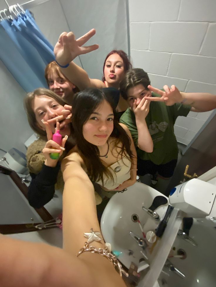 a group of young women standing in front of a bathroom mirror taking a selfie