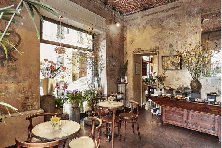 a restaurant with tables and chairs in front of large windows, potted plants on the wall